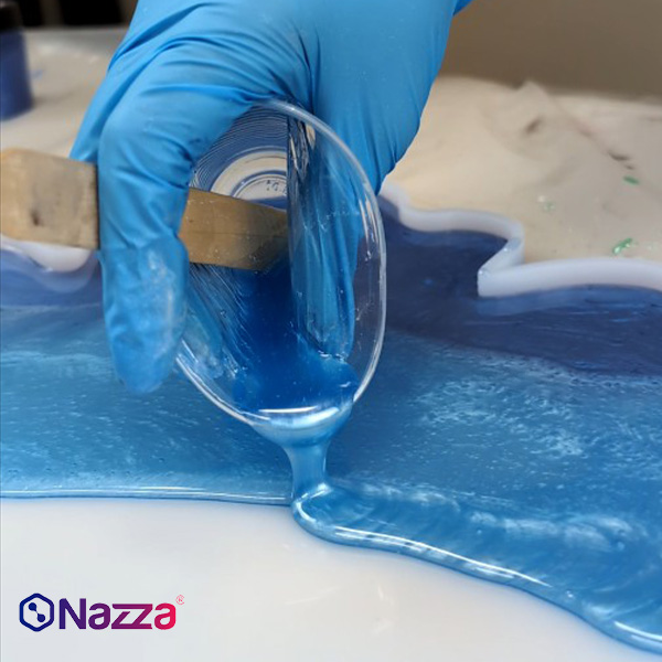 Aplicación de resina epoxi azul en un molde de silicona para manualidades.